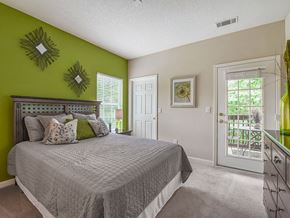 Asheville apartment for rent - A bedroom with a bed, green walls, and a window with blinds.