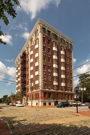 Norfolk apartment for rent - A tall red brick building with a flat roof and a parking lot in front.