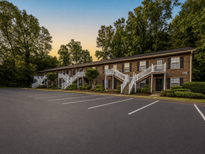 Winston Salem apartment for rent - A parking lot in front of a building with a staircase leading to the entrance.