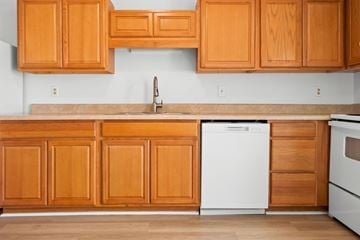 Fayetteville apartment for rent - A kitchen with wooden cabinets and a white dishwasher.