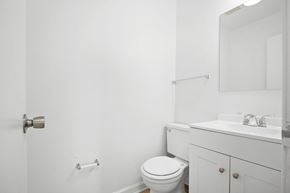 Fayetteville apartment for rent - A white bathroom with a toilet, sink, and mirror.
