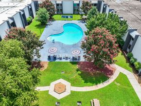 Burlington apartment for rent - A swimming pool surrounded by trees and a building in the background.