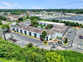 Burlington apartment for rent - A large industrial building with a parking lot in front.
