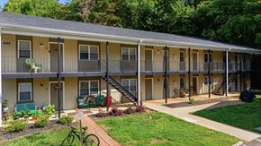 Winston Salem apartment for rent - Apartment complex with greenery and a bicycle parked in front.