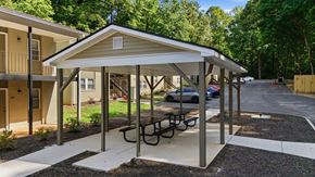 Winston Salem apartment for rent - A covered picnic area with a table and chairs is located in front of a building.