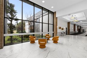 Fayetteville apartment for rent - A spacious lobby with yellow chairs and a marble floor.