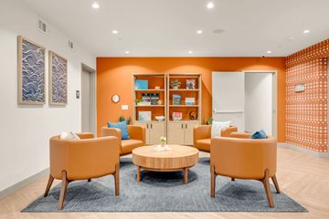 Ocean Isle Beach apartment for rent - A living room with orange chairs and a round table.