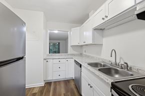 Winston Salem apartment for rent - A kitchen with white cabinets and a stainless steel refrigerator.