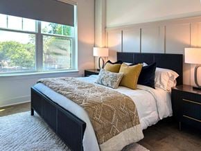 Asheville apartment for rent - A bedroom with a large bed and a window overlooking a tree-filled area.