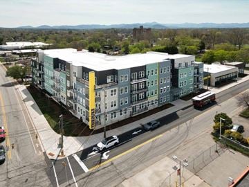 Asheville apartment for rent - A large apartment complex is situated on a street corner with a view of the mountains in the distance.