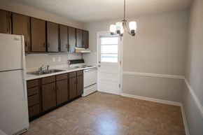 Fayetteville apartment for rent - A kitchen with brown cabinets and a white fridge.