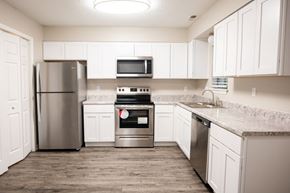 Apex townhouse for rent - A kitchen with white cabinets and a stainless steel refrigerator.