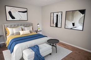 Fayetteville apartment for rent - A bedroom with a bed, a chair, and two framed artworks on the wall.