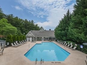 Asheville apartment for rent - A pool surrounded by trees and a building in the background.