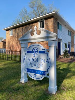 Fayetteville apartment for rent - A sign for Carolina Place Apartments stands in front of a brick building.