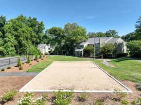 Winston Salem apartment for rent - A sand volleyball court is surrounded by trees and houses.