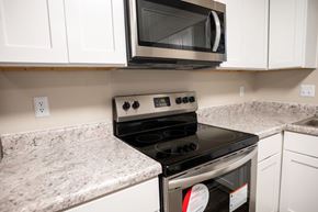 Apex apartment for rent - A modern kitchen with a black stove top oven and white cabinets.