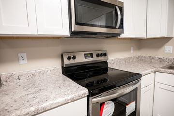 Apex townhouse for rent - A modern kitchen with a black stove top oven and white cabinets.