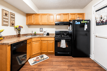 Asheville apartment for rent - A kitchen with wooden cabinets and black appliances.
