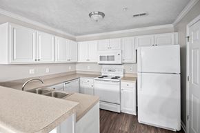 Fayetteville apartment for rent - A white kitchen with a refrigerator, sink, and stove.