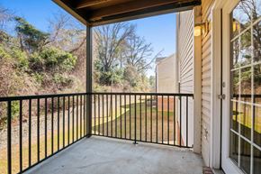 Fayetteville apartment for rent - A balcony with a black railing and a view of a green lawn and trees.