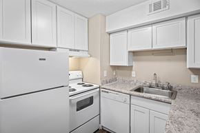 Fayetteville townhouse for rent - A white kitchen with a refrigerator, stove, and sink.