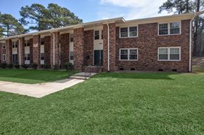 Fayetteville apartment for rent - A brick building with a green lawn in front.