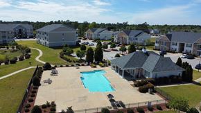 Fayetteville apartment for rent - A swimming pool in the middle of a grassy area surrounded by houses.