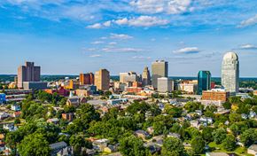 Winston Salem apartment for rent - A cityscape with a mix of modern and older buildings, surrounded by greenery.