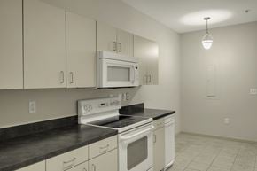 Durham apartment for rent - A kitchen with white cabinets and black countertops.