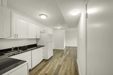 Durham apartment for rent - A kitchen with white cabinets and a black counter top.