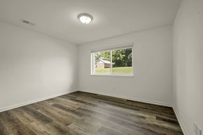 Durham apartment for rent - A room with wooden flooring and a window showing a house and trees outside.