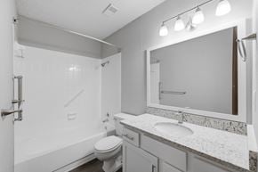 Winston Salem apartment for rent - A white bathroom with a toilet, sink, and mirror.