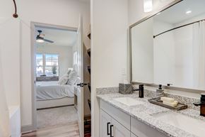 Asheville apartment for rent - A bathroom with a mirror, sink, and a bedroom with a bed and a window.