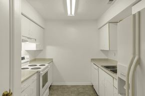 Durham apartment for rent - A white kitchen with a stove, sink, and cabinets.