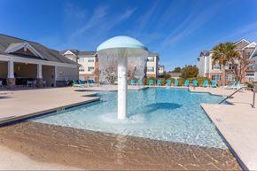 Jacksonville apartment for rent - A large fountain in the middle of a pool surrounded by chairs.