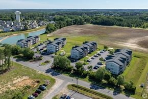 Raeford apartment for rent - A bird's eye view of a residential area with apartment buildings, a parking lot, and a water body.
