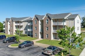 Raeford apartment for rent - A parking lot in front of a building with cars parked.
