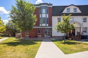Ottawa apartment for rent - A red brick building with a white trim and a black roof sits next to a white house with a red roof.