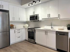 Ottawa apartment for rent - A modern kitchen with white cabinets and stainless steel appliances.