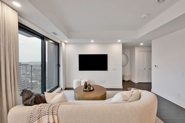 Ottawa apartment for rent - A modern living room with a large couch and a flat screen TV mounted on the wall.