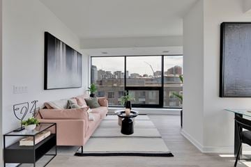 Ottawa apartment for rent - A modern living room with a pink couch and a large window overlooking the city.