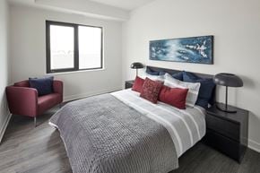 Ottawa apartment for rent - a bedroom with a bed and a chair and a window