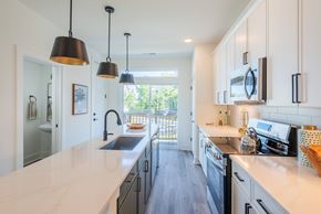 Charlotte townhouse for rent - A kitchen with a white counter top and black pendant lights.