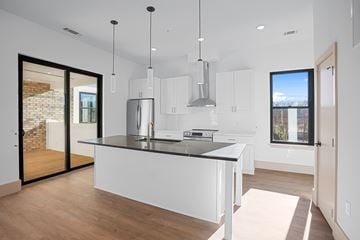 Charlotte townhouse for rent - A modern kitchen with white cabinets and a black countertop.