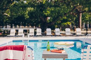 Savannah apartment for rent - A table with a bottle, glasses and a book sits by a pool.
