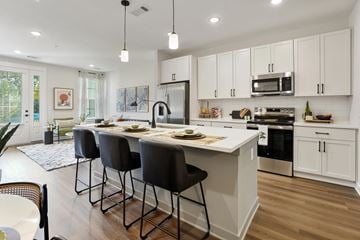 Charlotte townhouse for rent - A kitchen with white cabinets and a large island with four chairs.