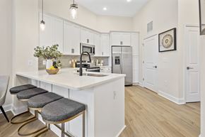 Cornelius apartment for rent - A kitchen with white cabinets and a white island with a vase of flowers on it.