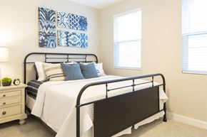Savannah apartment for rent - A bedroom with a black metal bed frame and a white bedspread.