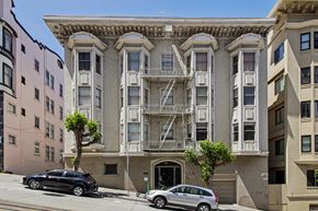 San Francisco apartment for rent - A black car is parked on the street in front of a tan building with a tree in front of it.